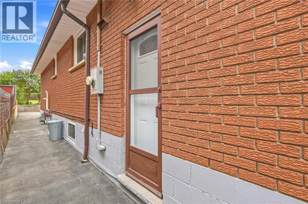 Brick exterior with a side entry door and a concrete pathway - 137 Picton Street E, Hamilton, ON