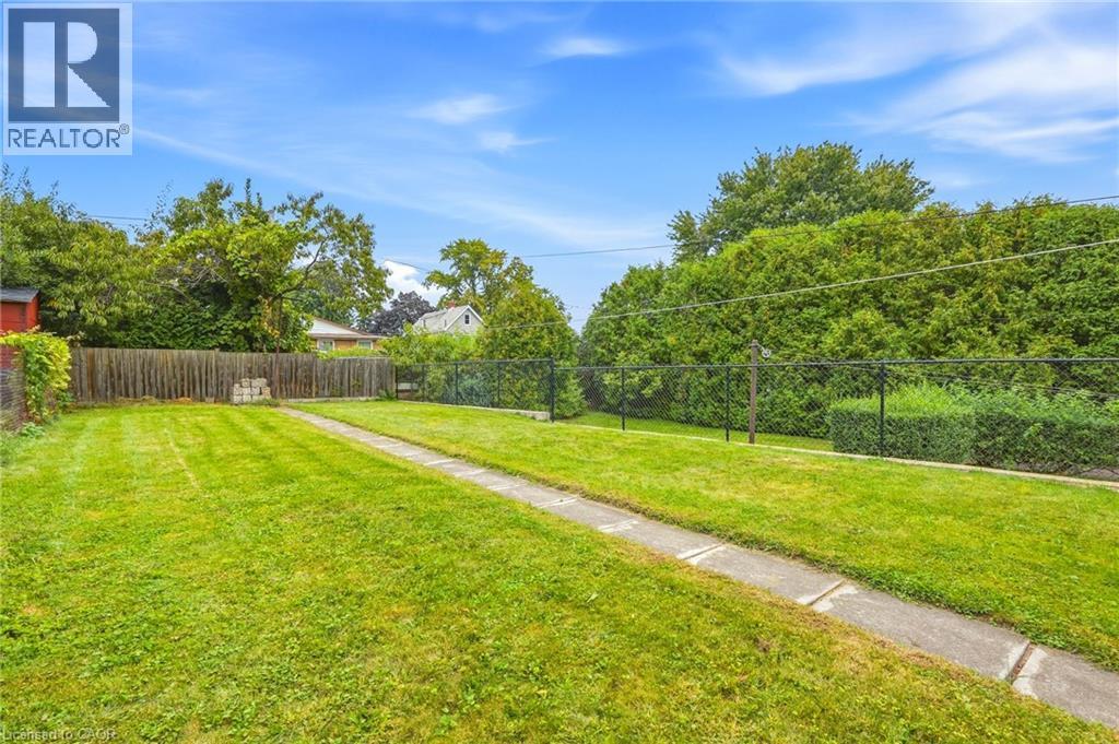 Expansive grassy yard with a concrete pathway and mature perimeter trees - 137 Picton Street E, Hamilton, ON