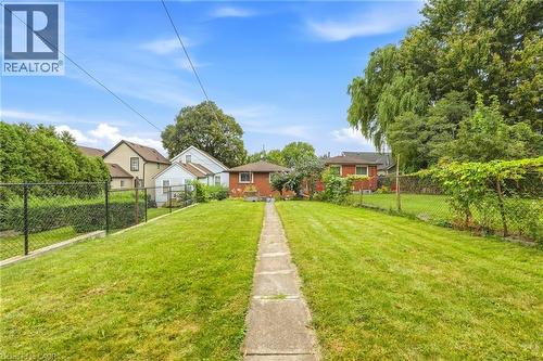 Expansive green lawn with a central concrete pathway and chain-link fencing - 137 Picton Street E, Hamilton, ON 