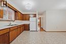 Kitchen featuring wood-finish cabinetry, a double basin stainless steel sink with a gooseneck faucet, a white refrigerator, and patterned floor tile - 137 Picton Street E, Hamilton, ON 