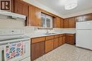 Kitchen featuring wood-finish cabinetry, white countertops, a stainless steel sink, and white appliances - 137 Picton Street E, Hamilton, ON 