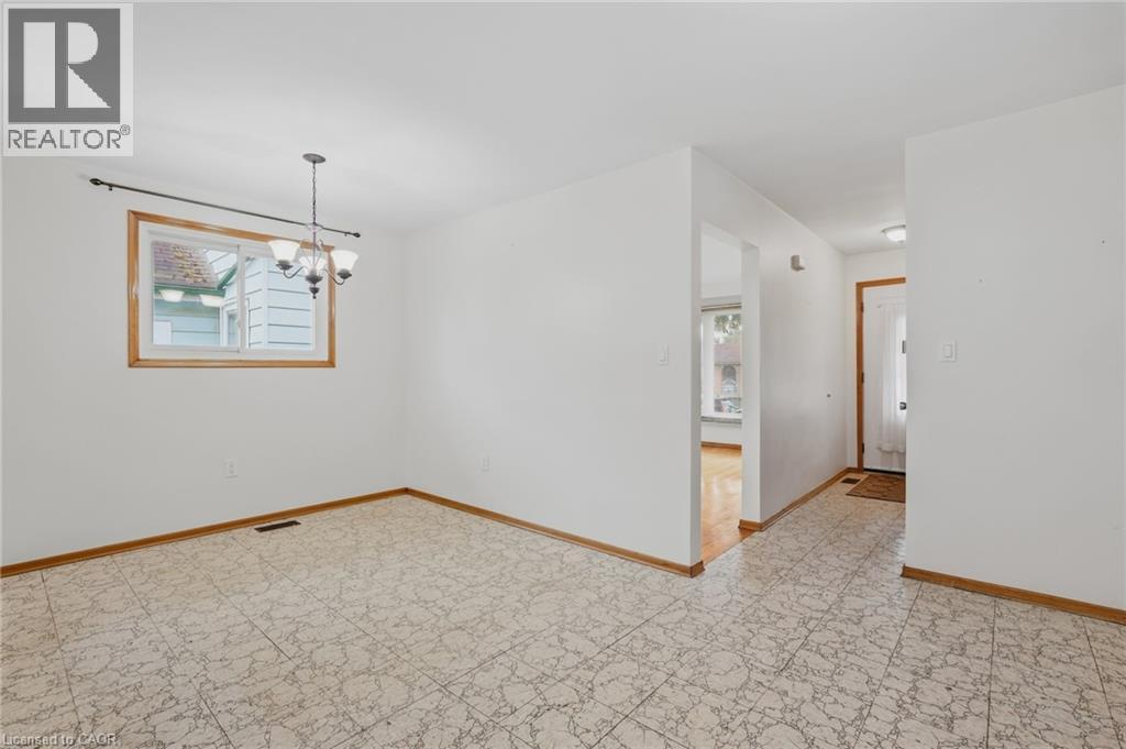 White interior walls, patterned floor tiles, overhead lighting fixture, and natural wood trim around window and doorways - 137 Picton Street E, Hamilton, ON