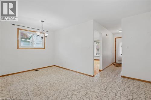 White interior walls, patterned floor tiles, overhead lighting fixture, and natural wood trim around window and doorways - 137 Picton Street E, Hamilton, ON 