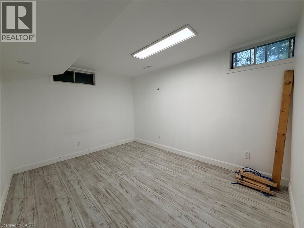 Recessed and surface-mounted lighting illuminate this room, featuring wood-finish flooring and multiple windows - 450 Bridge Street W, Waterloo, ON
