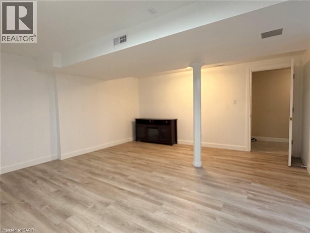 Spacious room featuring wood-finish flooring, white walls, and a visible doorway - 450 Bridge Street W, Waterloo, ON