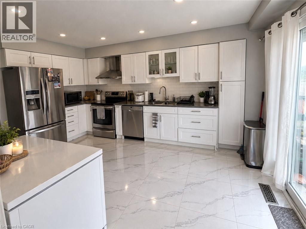 Kitchen featuring recessed lighting, white cabinetry, stainless steel appliances, a tile backsplash, and white tile flooring - 125 Fairgreen Close, Cambridge, ON