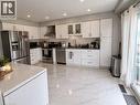 Kitchen featuring recessed lighting, white cabinetry, stainless steel appliances, a tile backsplash, and white tile flooring - 125 Fairgreen Close, Cambridge, ON 