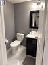 White tile flooring with subtle veining, dark vanity with a white countertop, and a wall-mounted light fixture - 125 Fairgreen Close, Cambridge, ON 