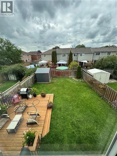 Expansive backyard featuring a wood deck, green lawn, two storage sheds, and wood fencing - 125 Fairgreen Close, Cambridge, ON 