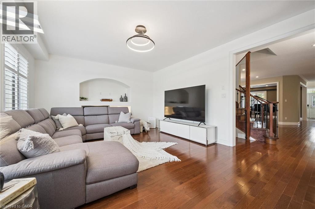 Hardwood flooring throughout, arched wall niche, contemporary chandelier, plantation shutters, and a wooden staircase with iron balusters - 517 Topper Woods Crescent, Kitchener, ON