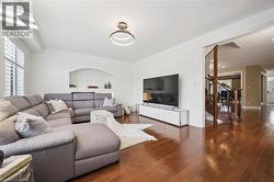 Hardwood flooring throughout, arched wall niche, contemporary chandelier, plantation shutters, and a wooden staircase with iron balusters -