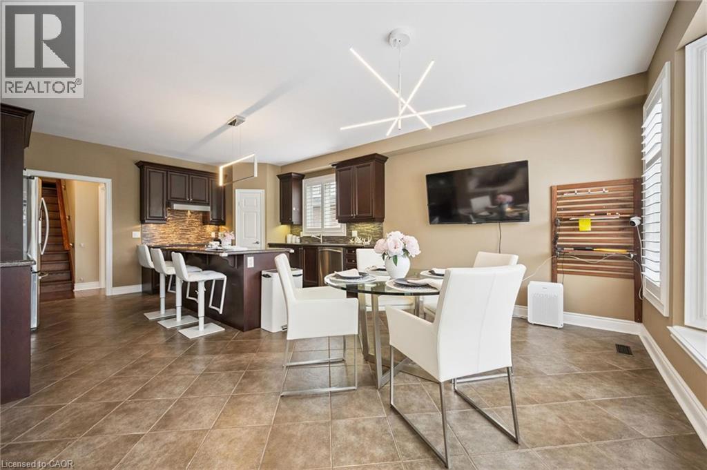 Dark wood cabinetry, stainless steel appliances, tile flooring, modern light fixtures, and window shutters - 517 Topper Woods Crescent, Kitchener, ON