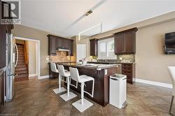 Kitchen featuring dark wood cabinetry, a central island with seating, stainless steel appliances, and tile flooring -