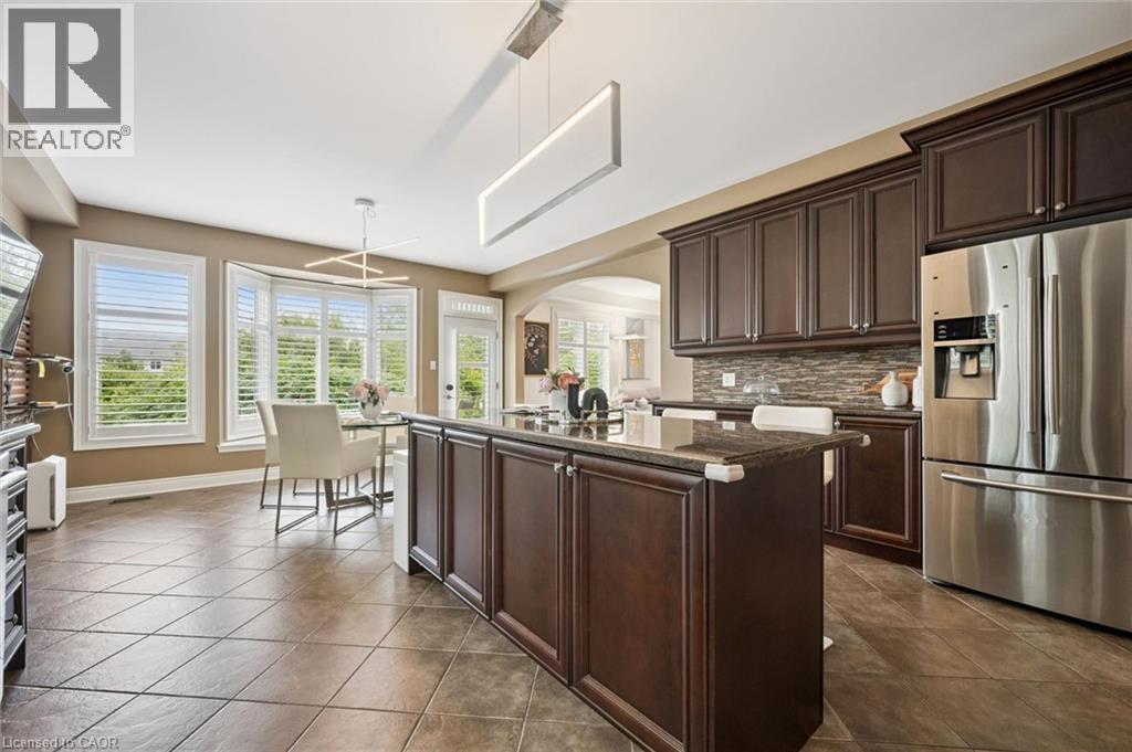 Expansive kitchen with a center island, dark wood-finish cabinetry, stainless steel appliances, and a tiled backsplash - 517 Topper Woods Crescent, Kitchener, ON