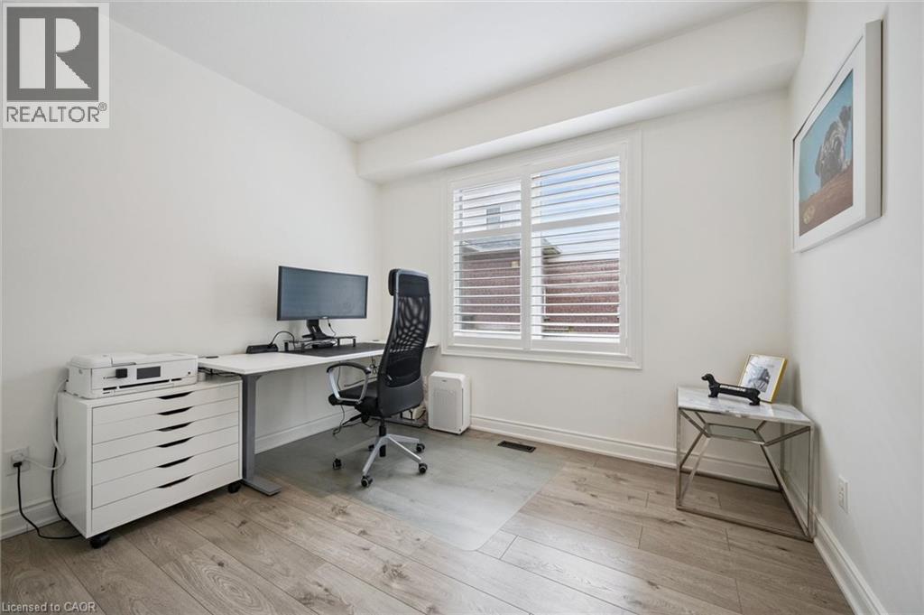 Bright room with wood-finish flooring, white walls, and a window featuring white plantation shutters - 517 Topper Woods Crescent, Kitchener, ON