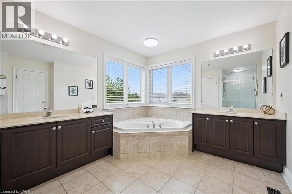 Dual vanities with integrated sinks, a corner jetted tub, large windows, and tiled flooring - 517 Topper Woods Crescent, Kitchener, ON