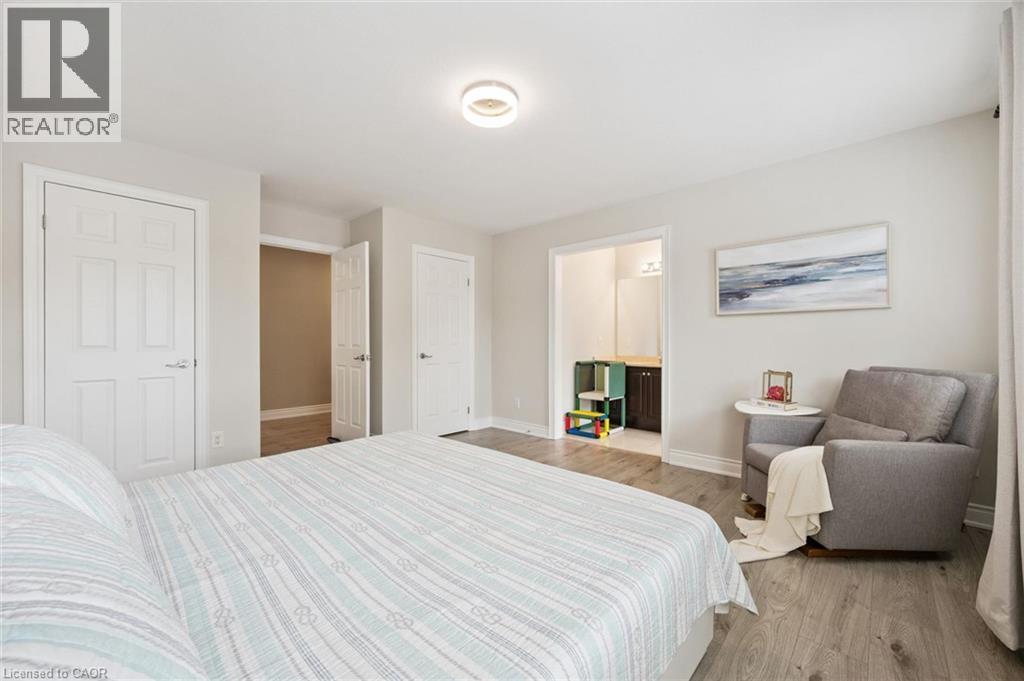 Spacious room featuring wood-finish flooring, light gray walls, and a contemporary ceiling light fixture - 517 Topper Woods Crescent, Kitchener, ON
