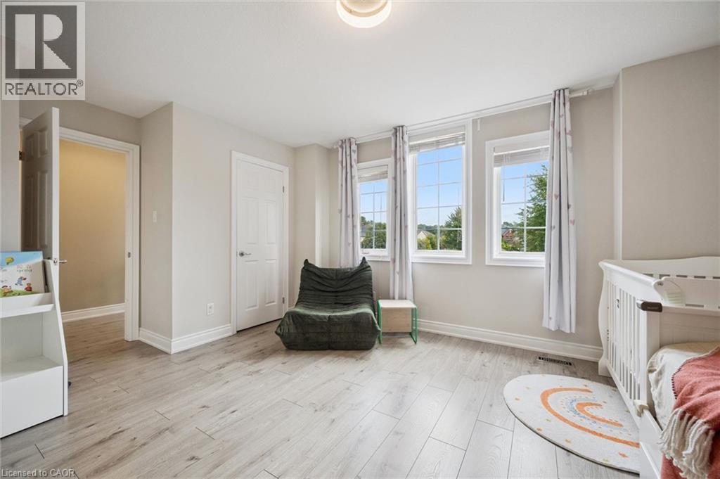 Recessed ceiling light, three large windows, light wood-finish flooring, white trim, and neutral wall tones - 517 Topper Woods Crescent, Kitchener, ON