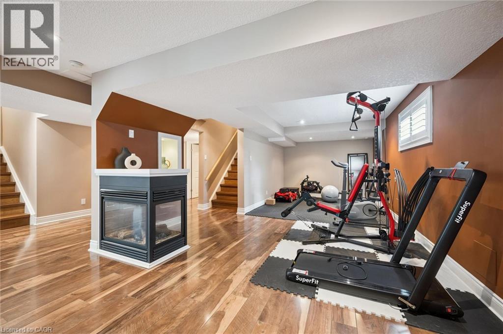 Wood-finish flooring, built-in fireplace, recessed lighting, and a window with white shutters - 517 Topper Woods Crescent, Kitchener, ON