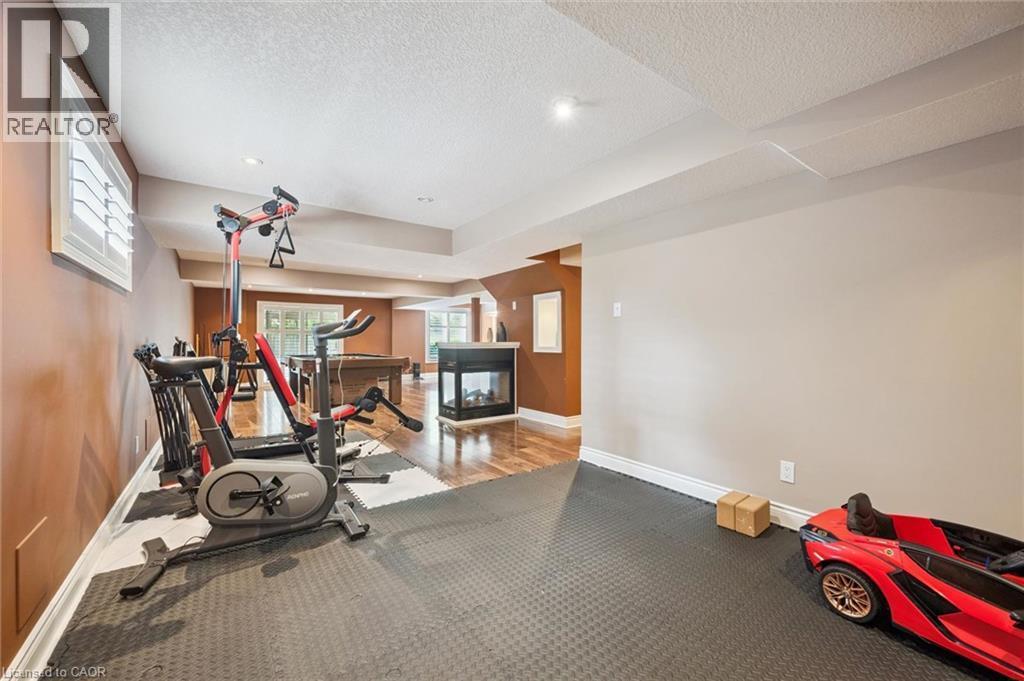 Spacious lower level featuring recessed lighting, a built-in fireplace, wood-finish flooring, and a window with plantation shutters - 517 Topper Woods Crescent, Kitchener, ON