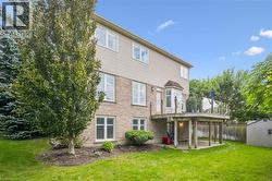 Expansive rear yard featuring a wooden deck with glass railing, a bay window, and a storage shed -