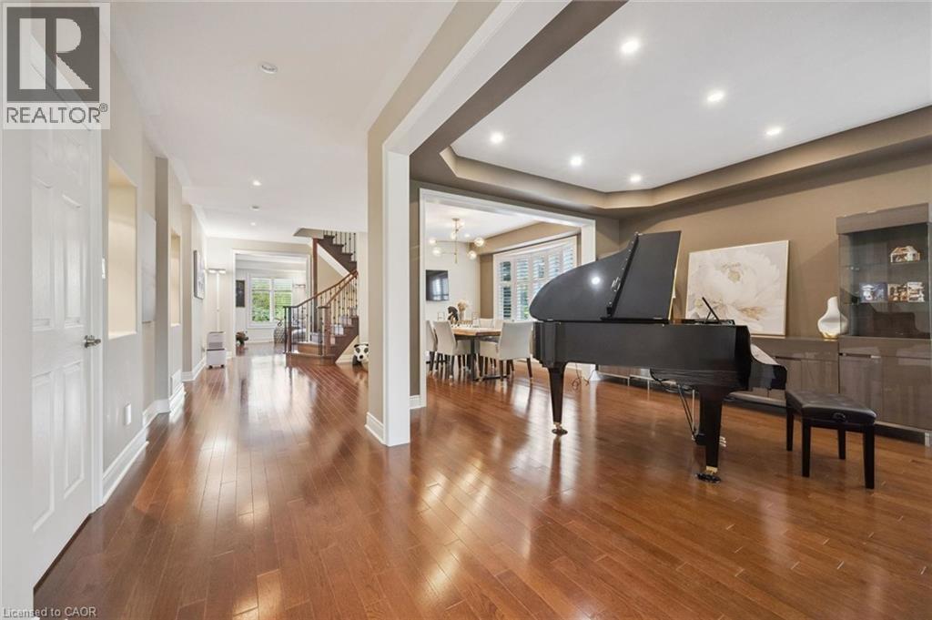 Elegant open-concept living space featuring rich wood-finish flooring throughout, architectural ceiling beams with recessed lighting, and warm neutral wall tones - 517 Topper Woods Crescent, Kitchener, ON