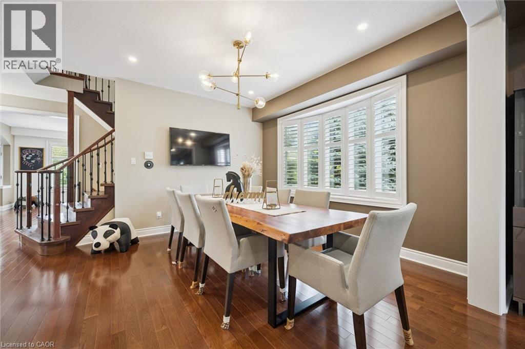 Rich wood-finish flooring, a contemporary chandelier, and a bay window with plantation shutters define this space - 517 Topper Woods Crescent, Kitchener, ON
