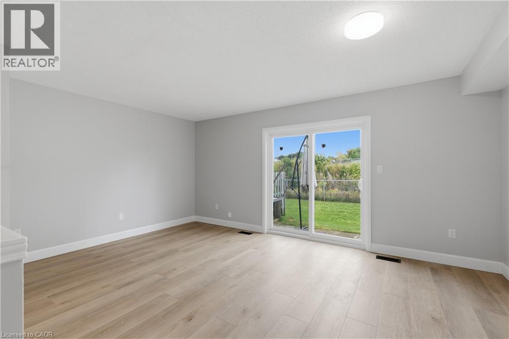 Light wood-finish flooring, white trim, and a sliding glass door to the backyard - 30 S Imperial Road Unit# 3, Guelph, ON
