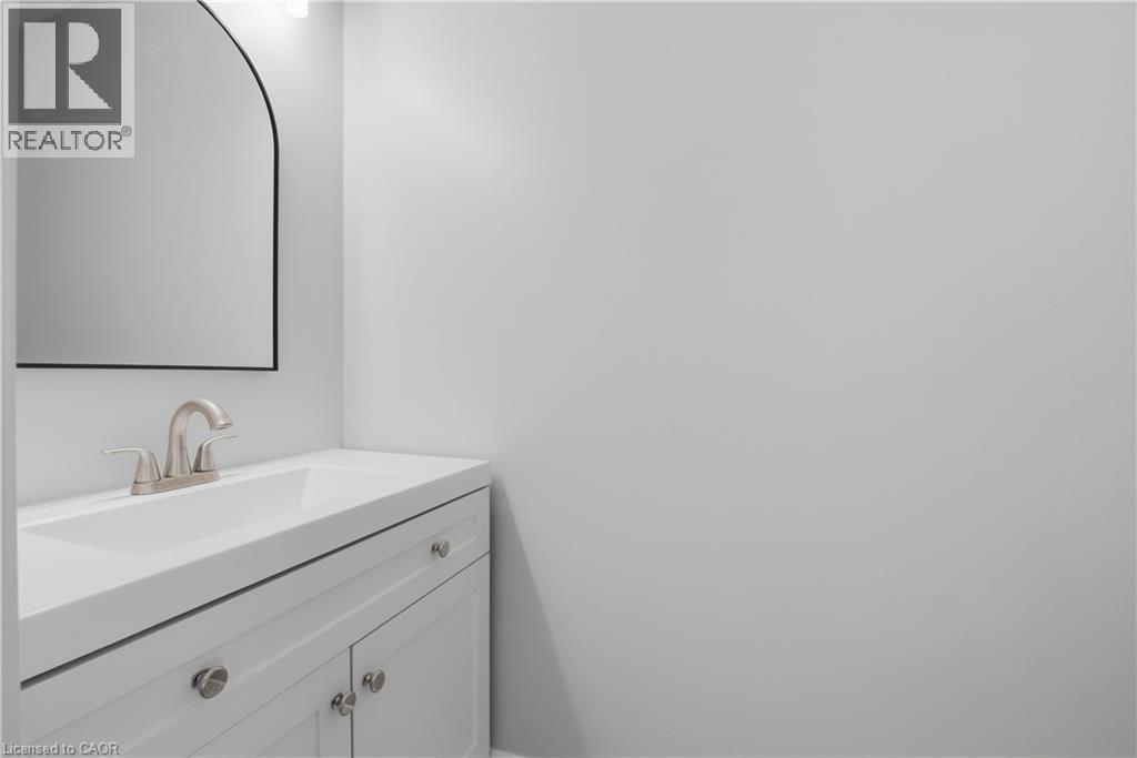 White vanity with brushed nickel hardware, integrated sink, and an arched mirror - 30 S Imperial Road Unit# 3, Guelph, ON