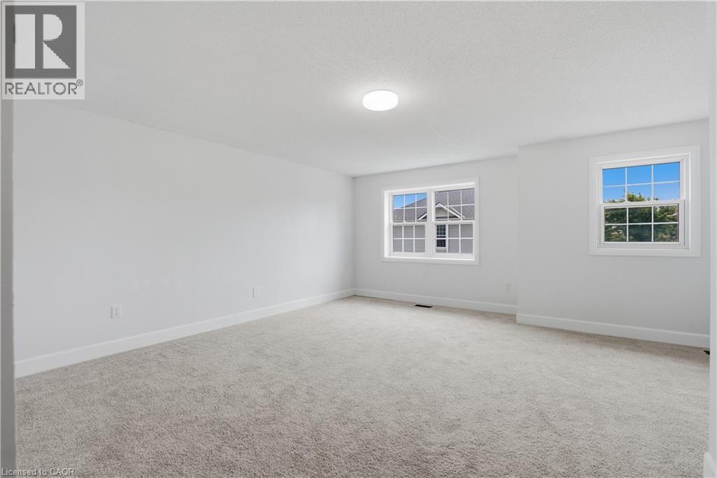 Light gray carpeting, white walls, two white-framed windows, and a ceiling-mounted light fixture - 30 S Imperial Road Unit# 3, Guelph, ON
