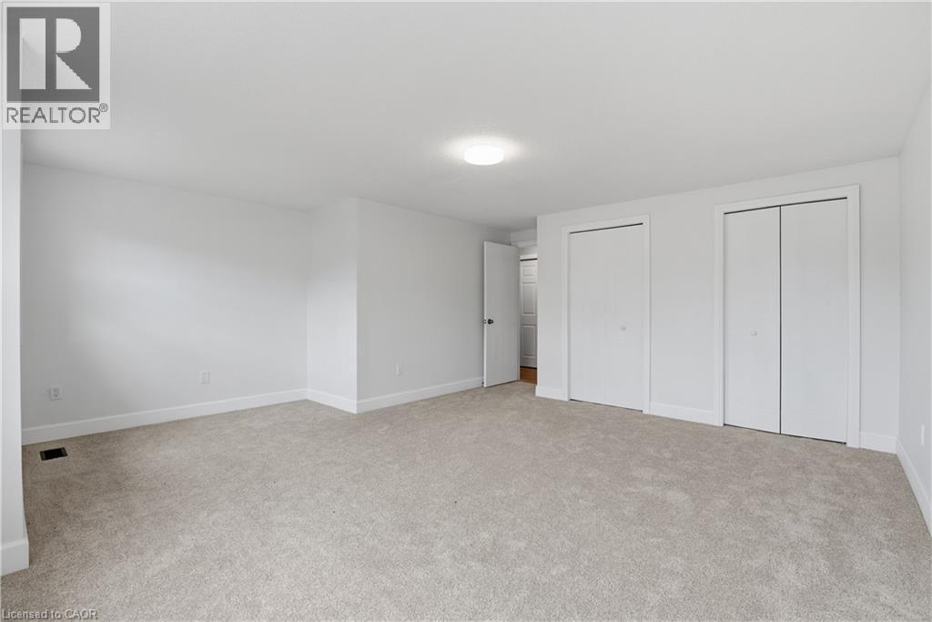 Neutral wall paint with carpet flooring, flush mount ceiling light, and multiple bi-fold closet doors - 30 S Imperial Road Unit# 3, Guelph, ON