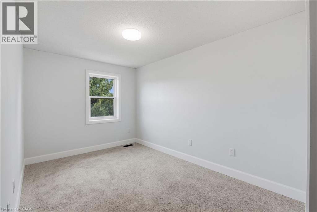 Neutral tone wall finish, white trim, light-colored carpeting, and a window with white casing - 30 S Imperial Road Unit# 3, Guelph, ON