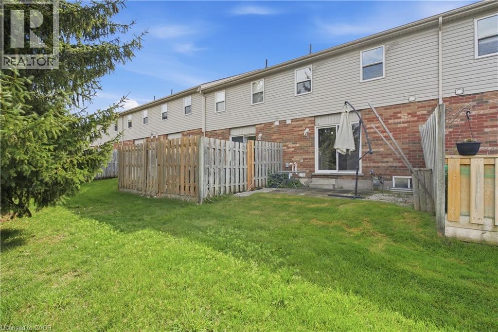 Private fenced backyard featuring a patio area, sliding glass door access, and a manicured lawn - 30 S Imperial Road Unit# 3, Guelph, ON