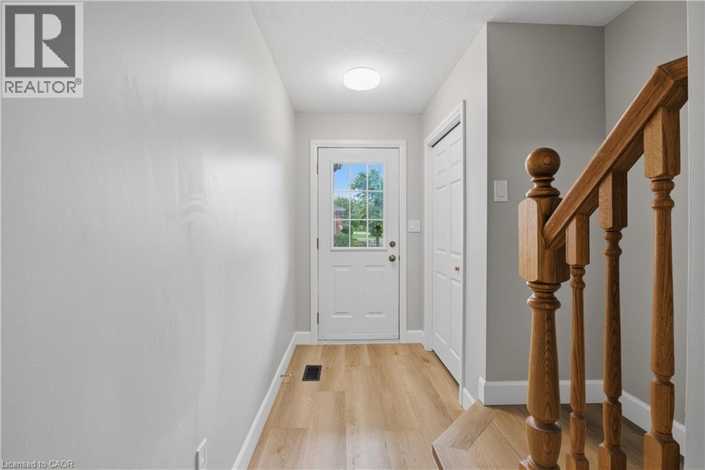 Entryway featuring wood-finish flooring, a white paneled door with windowpanes, a recessed ceiling light, and a built-in closet - 30 S Imperial Road Unit# 3, Guelph, ON