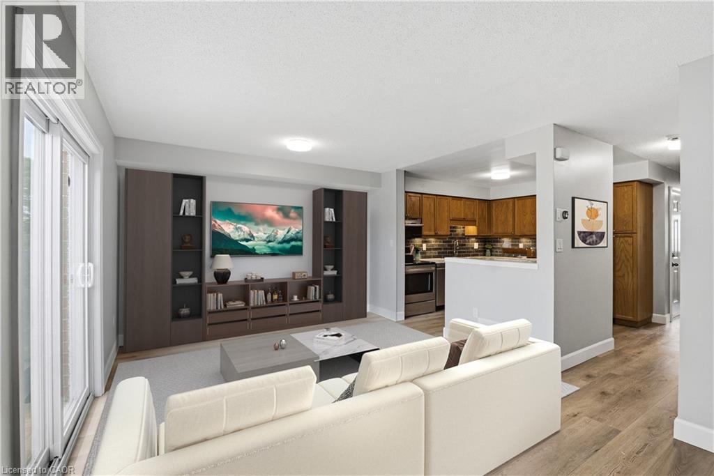 Open-concept living area featuring wood-finish flooring, built-in media storage, and a sliding glass door - 30 S Imperial Road Unit# 3, Guelph, ON