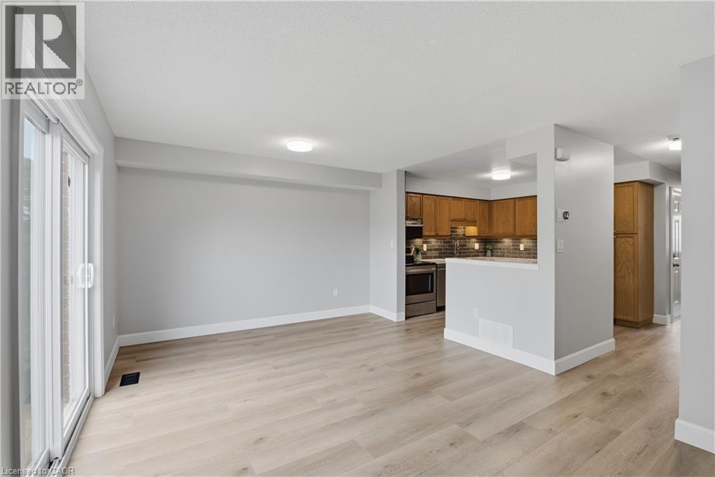 Light wood-finish flooring, sliding glass patio door, recessed lighting, wood cabinetry, and stainless steel appliances - 30 S Imperial Road Unit# 3, Guelph, ON