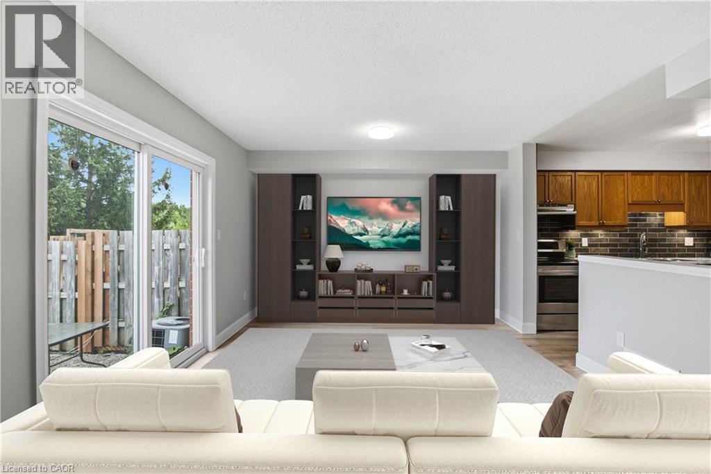 Built-in media console with open shelving, sliding glass door access to a private patio, wood-finish flooring, and recessed lighting - 30 S Imperial Road Unit# 3, Guelph, ON