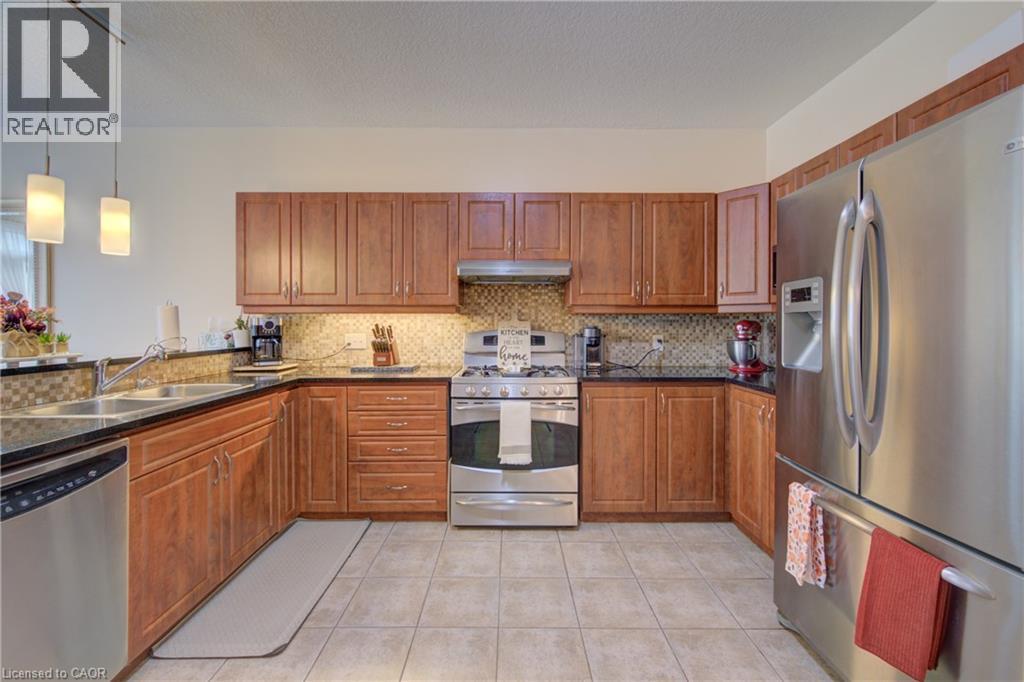 U-shaped kitchen with beautiful cabinetry, stainless steel appliances, dark granite countertops, and tiled flooring - 78 Stuckey Avenue, Baden, ON