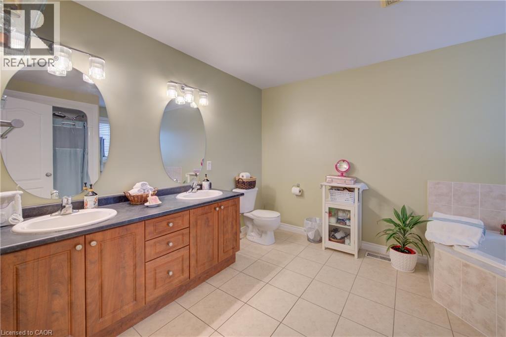 Double vanity with wood-finish cabinetry, dual sinks, and two mirrors - 78 Stuckey Avenue, Baden, ON