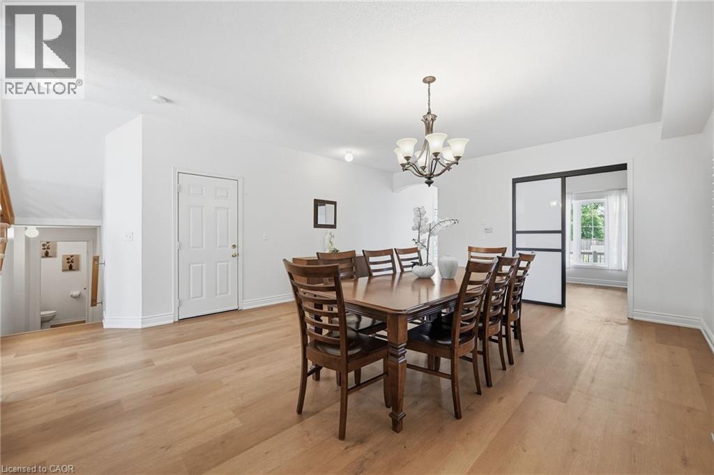 Spacious room with wood-finish flooring, a tiered chandelier, and a sliding door with frosted panels - 3198 Tim Dobbie Drive, Burlington, ON