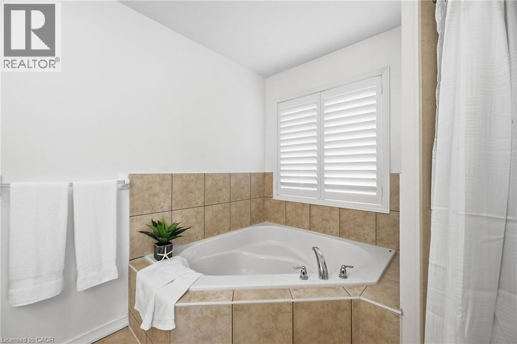 Corner soaking tub with tile surround, plantation shutters, and polished chrome fixtures - 3198 Tim Dobbie Drive, Burlington, ON