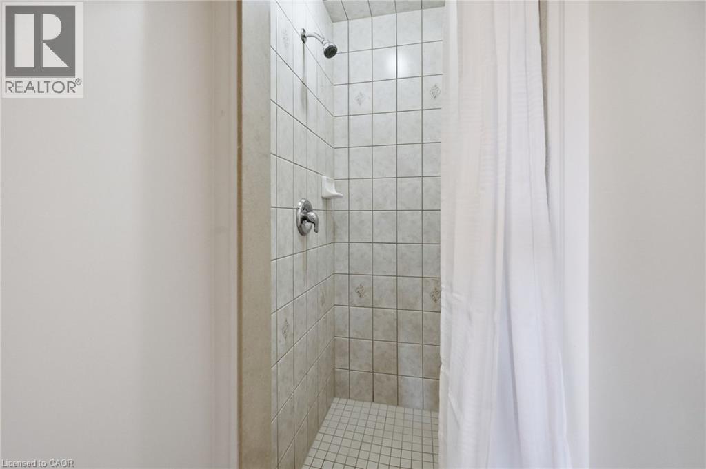 Tiled shower enclosure featuring a wall-mounted showerhead, chrome fixtures, and a corner soap dish - 3198 Tim Dobbie Drive, Burlington, ON
