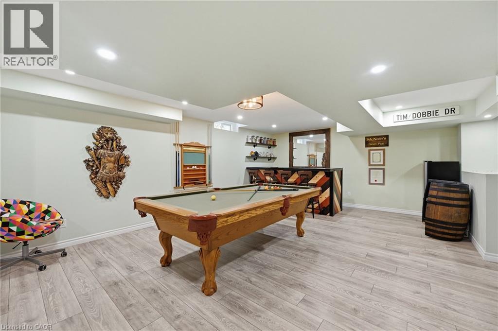 Finished lower level featuring recessed lighting, wood-finish flooring, and a built-in bar with shelving - 3198 Tim Dobbie Drive, Burlington, ON
