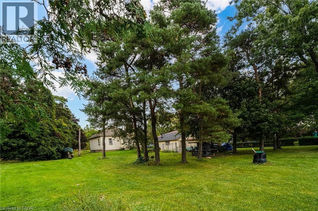 Expansive green lawn with mature trees and a partial view of a single-story structure - 1412 Old York Road, Burlington, ON
