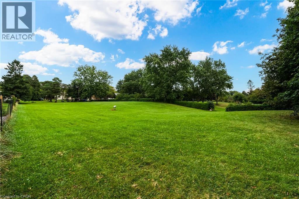 Expansive green lawn with mature trees and a manicured hedge line - 1412 Old York Road, Burlington, ON