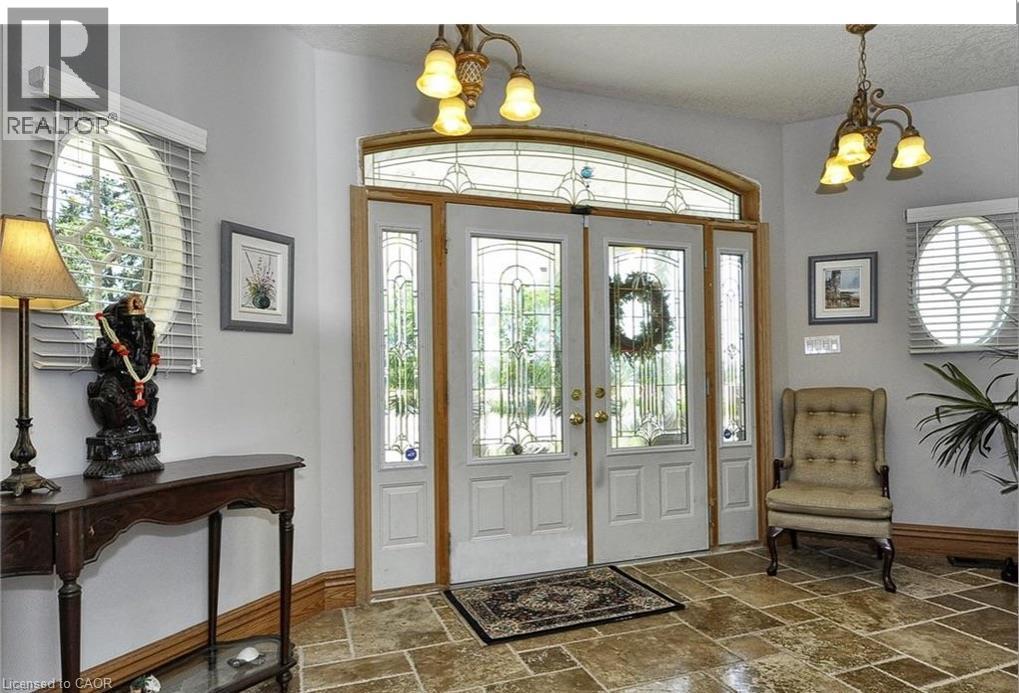 Double entry doors with decorative glass panels and an arched transom, flanked by two oval windows with blinds - 915 Briardean Road, Cambridge, ON