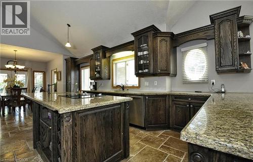 Kitchen featuring dark wood cabinetry, light-toned countertops, a central island with an integrated cooktop, and large format tile flooring - 915 Briardean Road, Cambridge, ON 