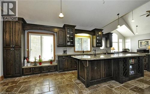 Spacious kitchen featuring dark wood cabinetry, a large kitchen island with integrated storage, light-toned countertops, and stone tile flooring - 915 Briardean Road, Cambridge, ON 