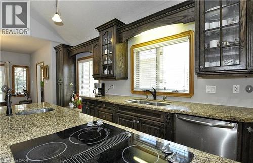 Kitchen featuring granite countertops, dark wood cabinetry, a built-in cooktop, stainless steel dishwasher, and a double basin sink - 915 Briardean Road, Cambridge, ON 
