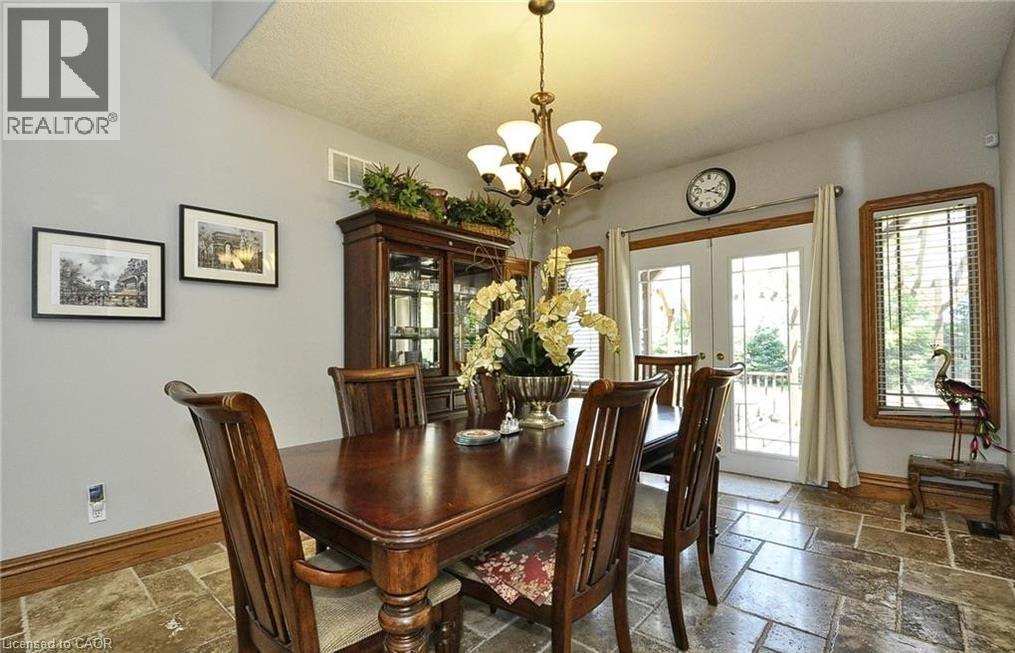 Vaulted ceiling, stone-look tile flooring, double French doors, wood trim, and a chandelier lighting fixture - 915 Briardean Road, Cambridge, ON